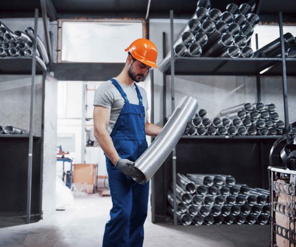 Portrait of a young worker in a hard hat at a large metalworking plant. Shiftman on the warehouse of finished products.